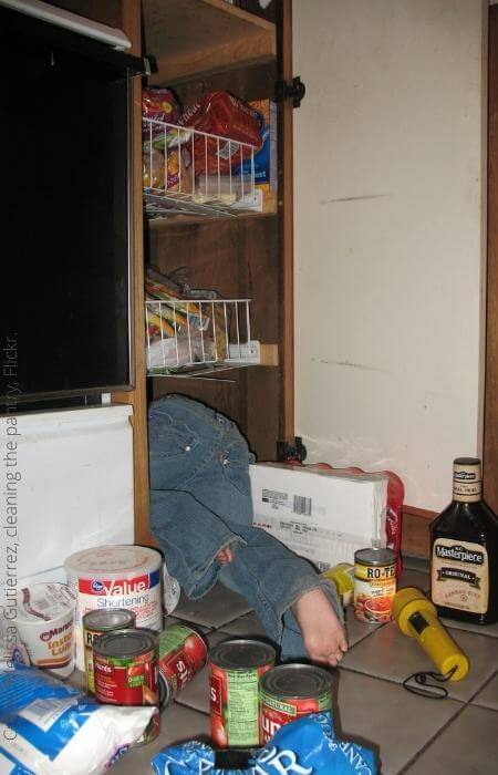 Small child having fun digging in a pantry cabinet.