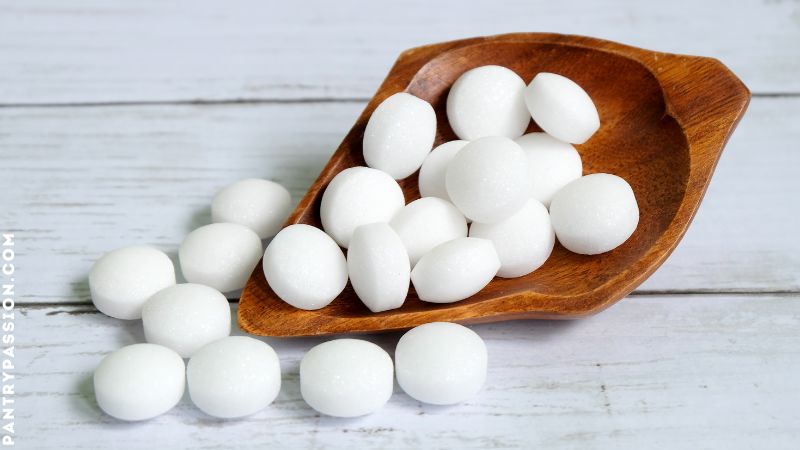 Wooden carved bowl filled with mothballs tumbling out.